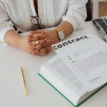 Iemand bekijkt een contract met documenten op een bureau (1)