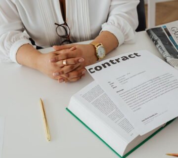 Iemand bekijkt een contract met documenten op een bureau (1)
